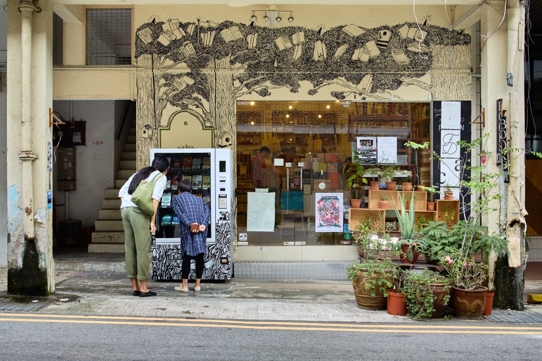 BooksActually storefront in Singapore with book vending machine and customers browsing.