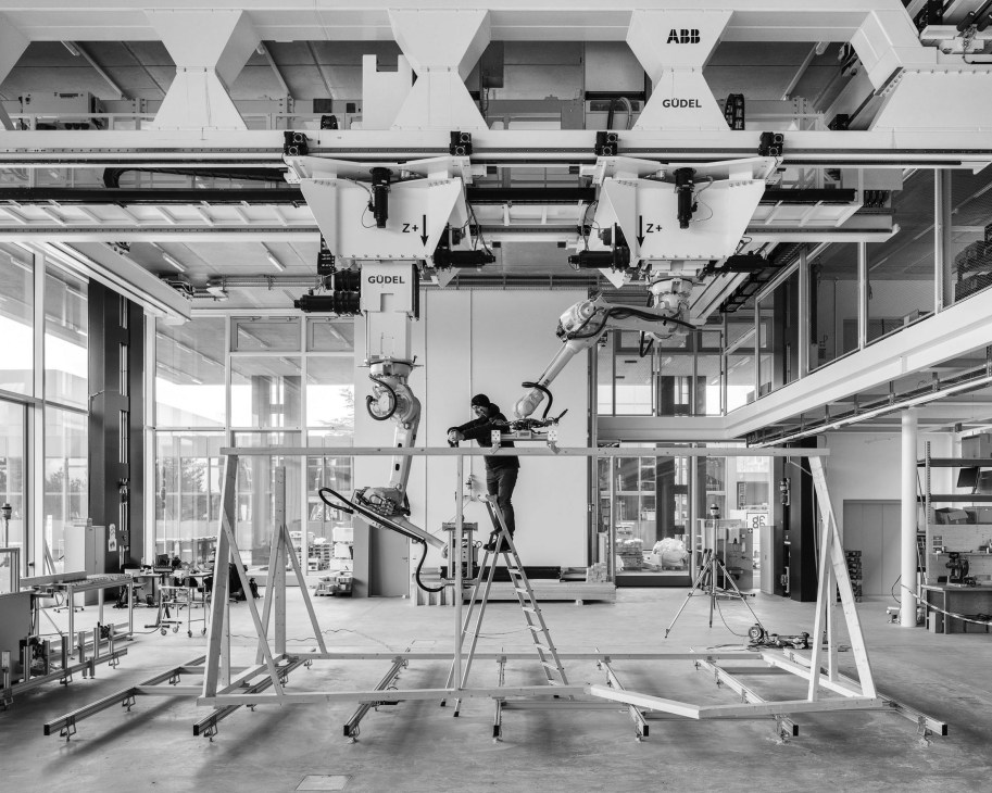 Robotic arms and a worker collaborating in a modern laboratory with industrial construction equipment.