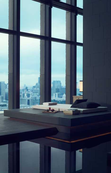 Modern minimalist room with floor-to-ceiling windows overlooking Tokyo cityscape and Mount Fuji in distance.