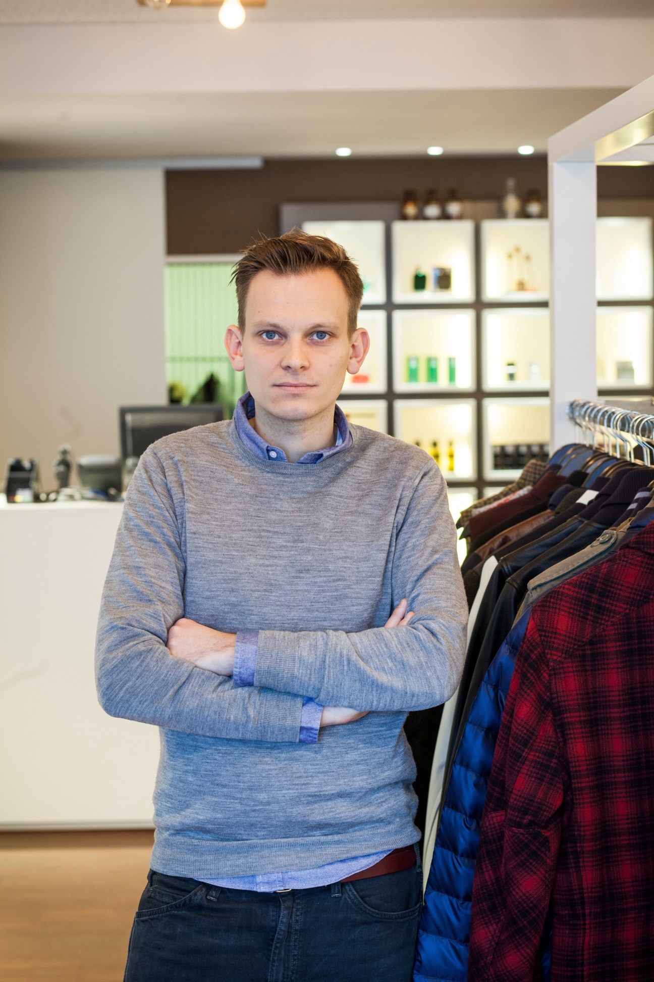 Daniel Steindorf, owner of Uebervart menswear shop in Frankfurt, standing in his store with clothing on display behind him.
