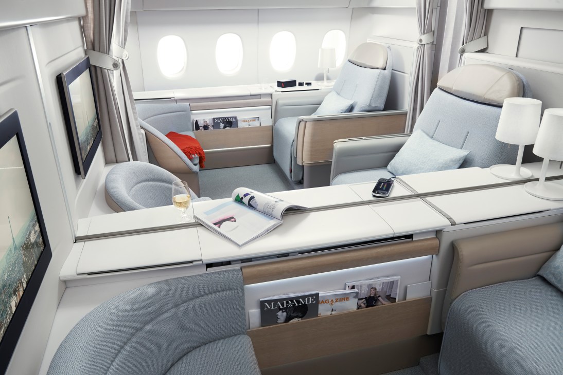 Air France's La Première first-class suite cabin with grey tones, wood finishes, and a flatbed seat.