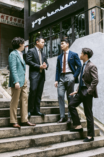 Chris Tang and colleagues at Prologue menswear shop in Hong Kong discussing made-to-order suits on exterior steps.
