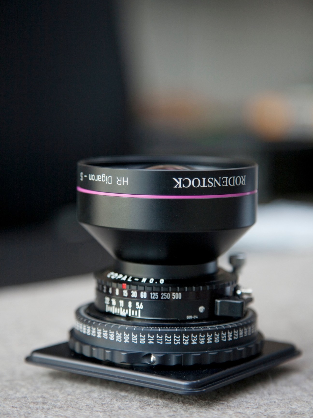 Rodenstock camera lens with pink band and precision aperture markings on black base.