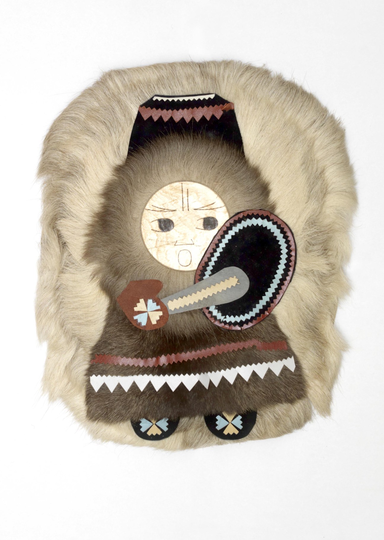 Indigenous Kamchatkan figure made from fur with decorative stitched details and a carved bone tool.