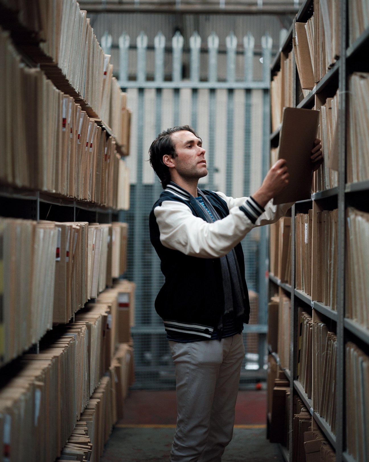 Man browsing vinyl records on shelves in The Vinyl Factory warehouse.
