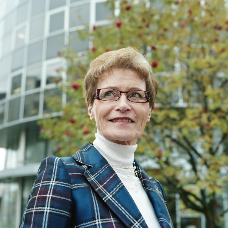 Marketta Kokkonen, Mayor of Espoo, Finland, smiling outdoors with ivy-covered building in background.