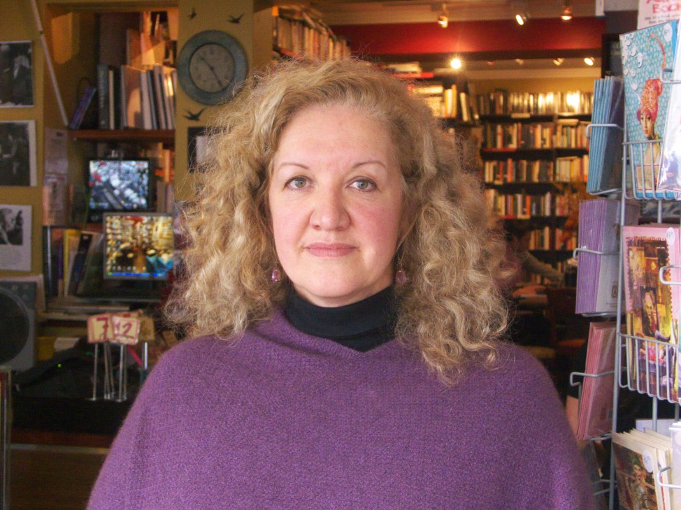Jane Turner, owner of Gertrude & Alice bookstore and café in Sydney, standing inside her shop surrounded by books and shelves.
