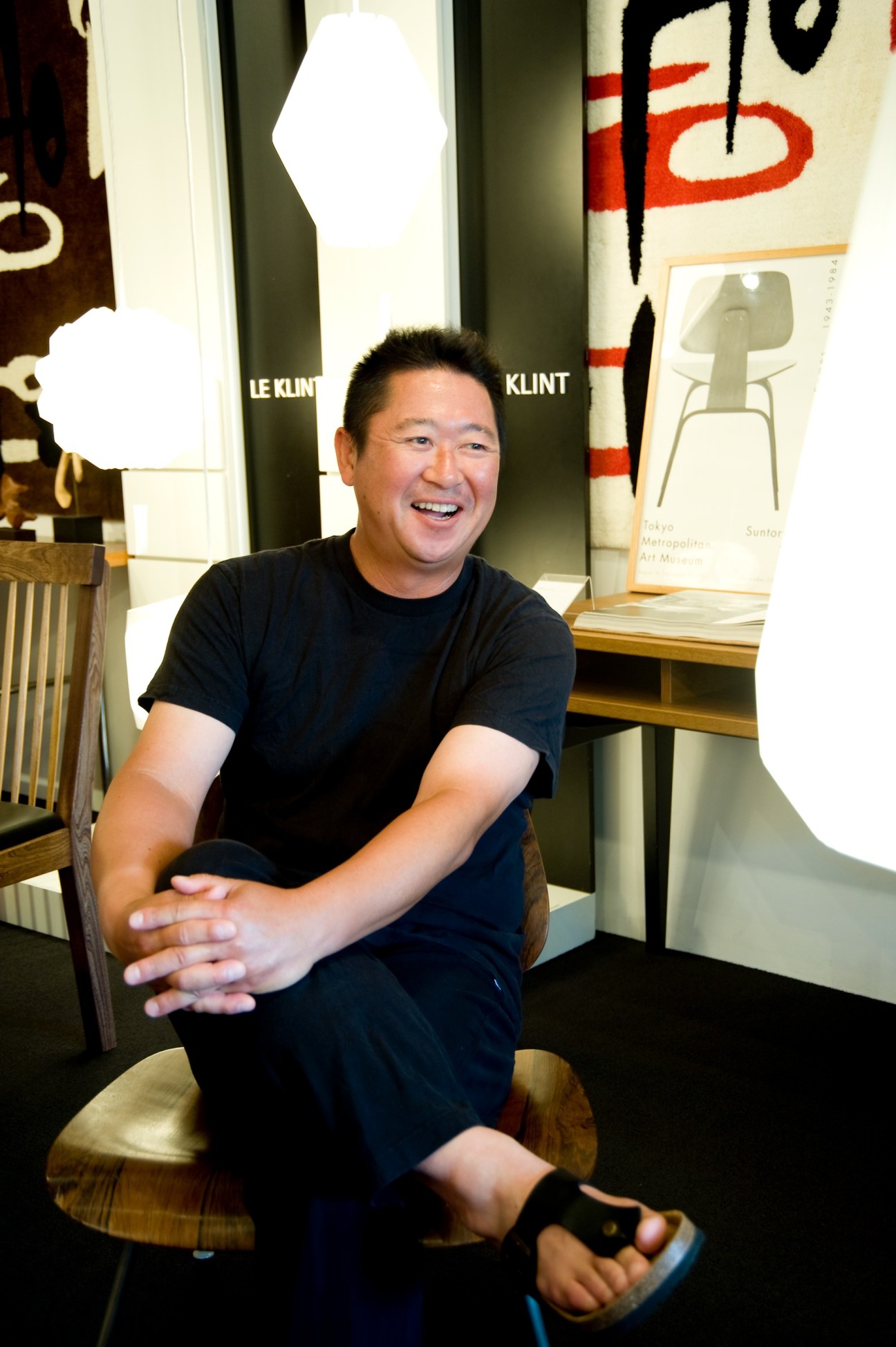 Taka Kosaka, owner of Meister furniture shop in Tokyo, sitting in his store among design pieces and lighting.