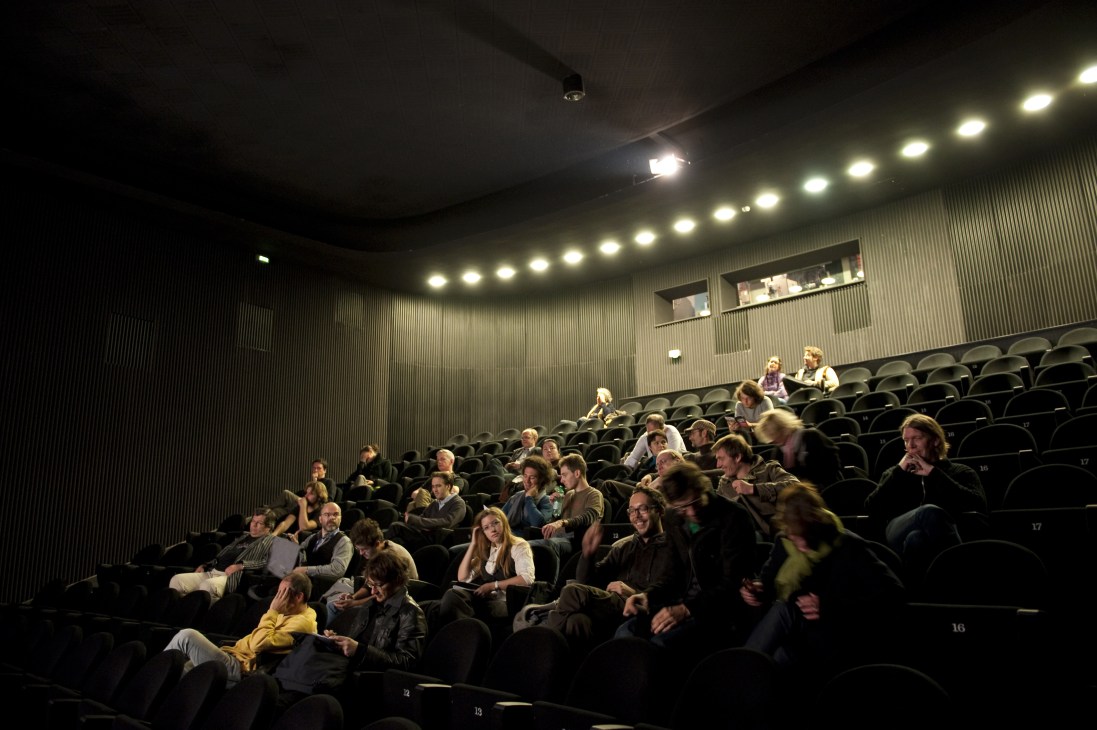 Audience members seated in a modern cinema during a film screening at Vienna Film Festival.