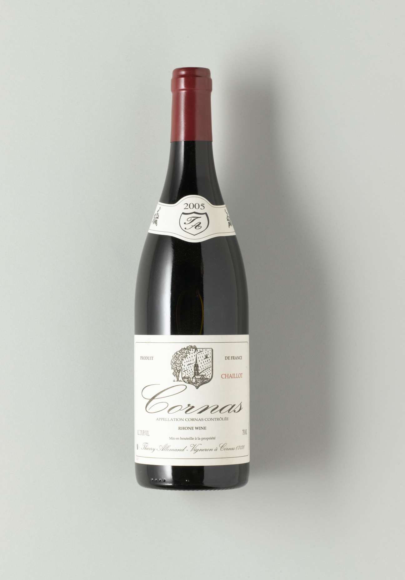 A bottle of 2005 Cornas wine with a red cap and white label against a neutral background.