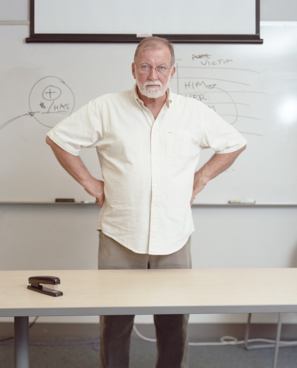 Tim McNulty, former newsman and lecturer at Northwestern's Medill School, stands at a desk with hands on hips in front of a whiteboard.