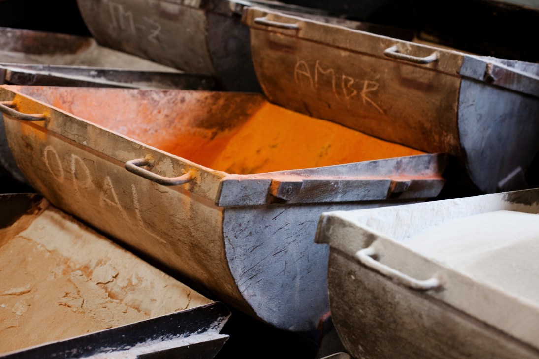 Molten orange glass visible in metal containers at Ajeto glassmaking factory.