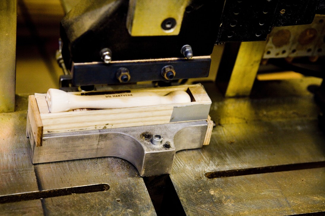 Iris Hantverk brush being stamped with branding logo on industrial stamping machine.