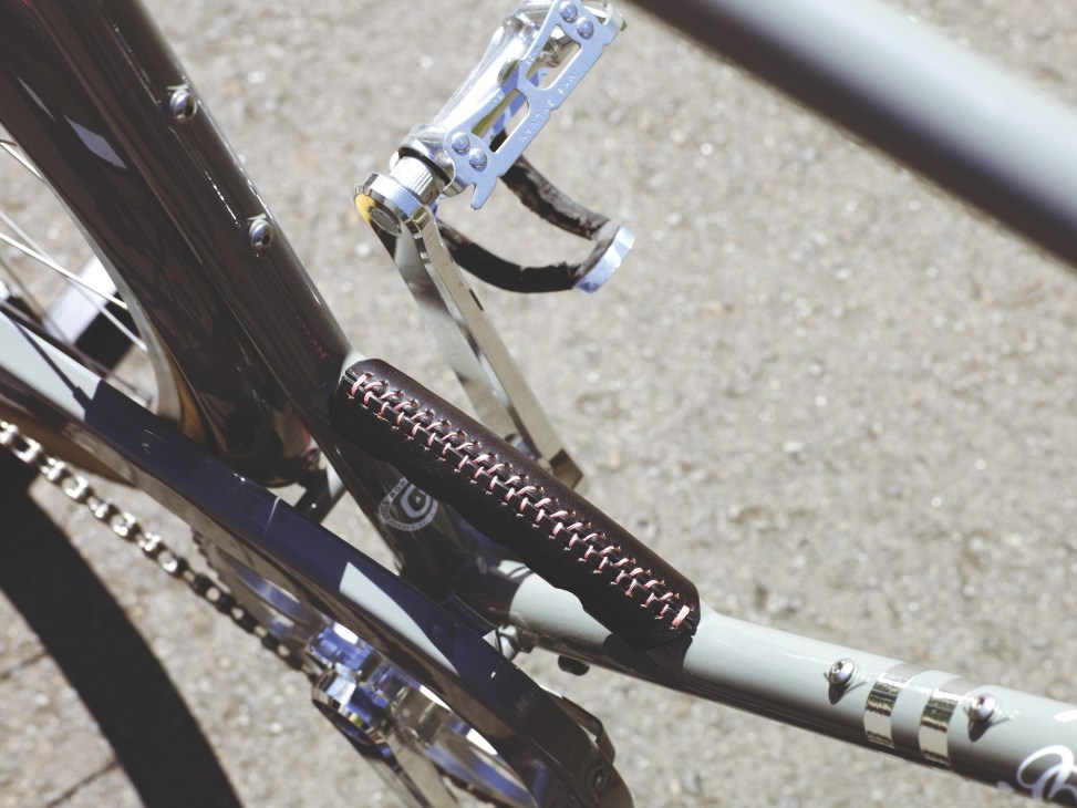Close-up of Beloved Rapha Every Day bicycle showing black frame, blue pedals, and handlebar grips with decorative stitching detail.