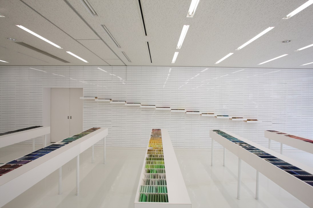 Interior of Takeo paper showroom in Tokyo with white walls and shelving displaying organized paper color samples.