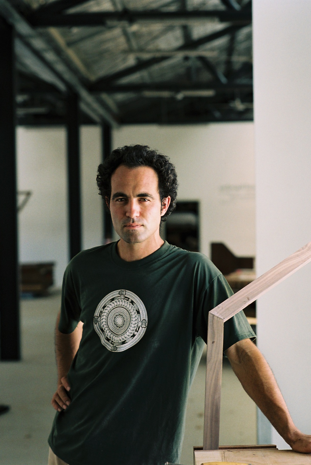 Nick Statham, sculptor and furniture designer, poses in The Pattern Shop workshop holding a wooden frame.
