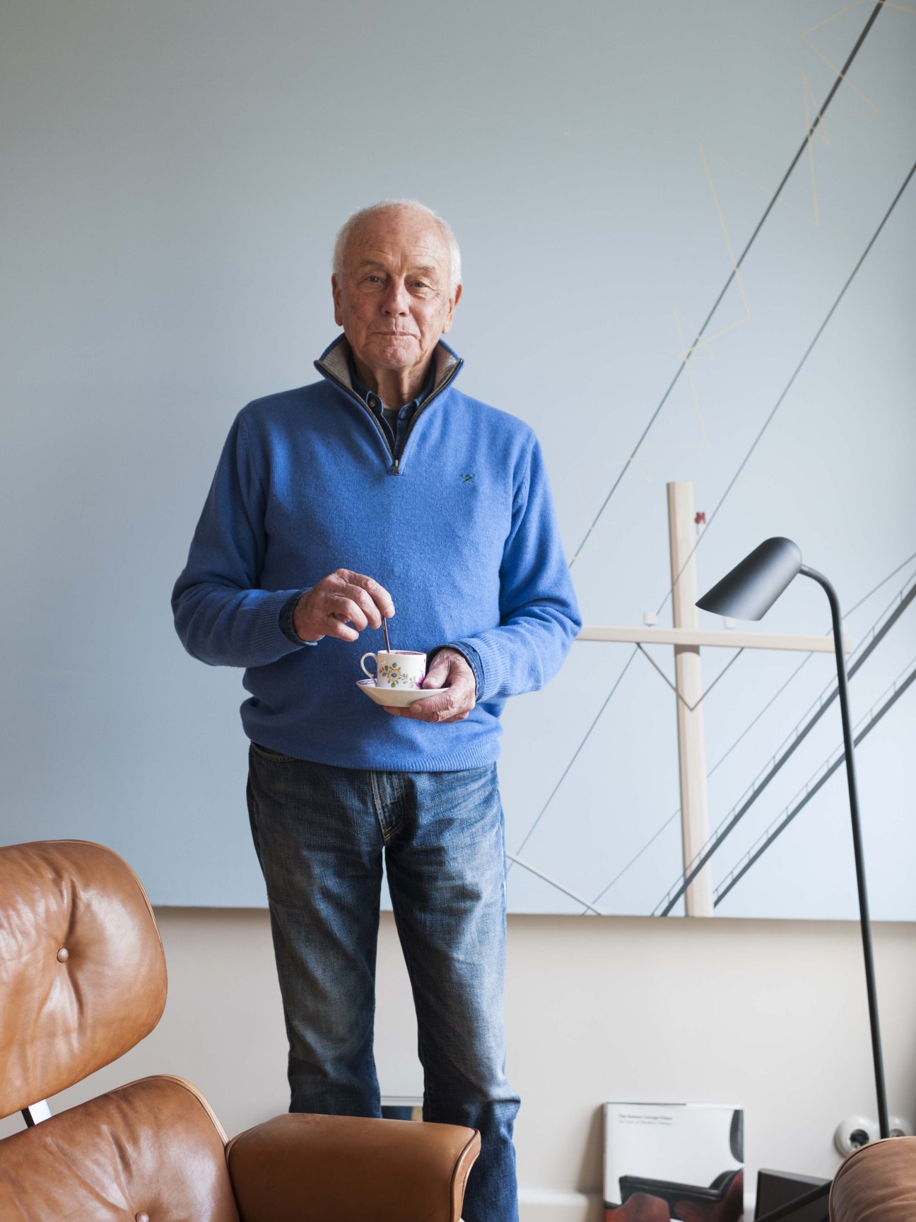 Helmut Trinks stands in a modernist apartment holding a coffee cup.