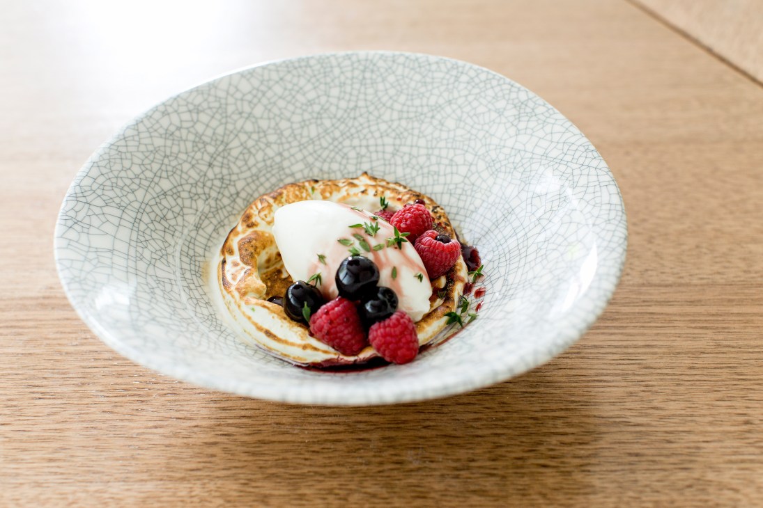 Buffalo yoghurt sorbet with Italian meringue, maraschino cherries, raspberries and thyme on a crackle-glazed plate.