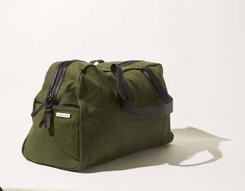 Olive-green cotton twill weekender bag by Everlane with black handles on white background.