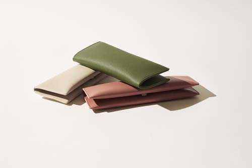 Stack of folded linen textiles in sage green, cream, mauve, and burgundy colors.