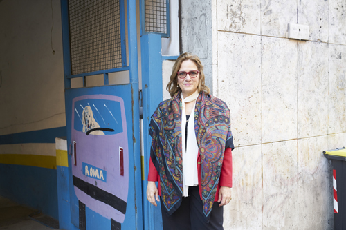 Rebecca Spitzmiller stands in front of a blue door marked AMMA in a Rome street.