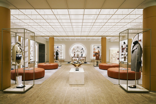 Interior of Tod's Studios Milan flagship store with minimalist design, orange seating, wooden flooring and display cases.