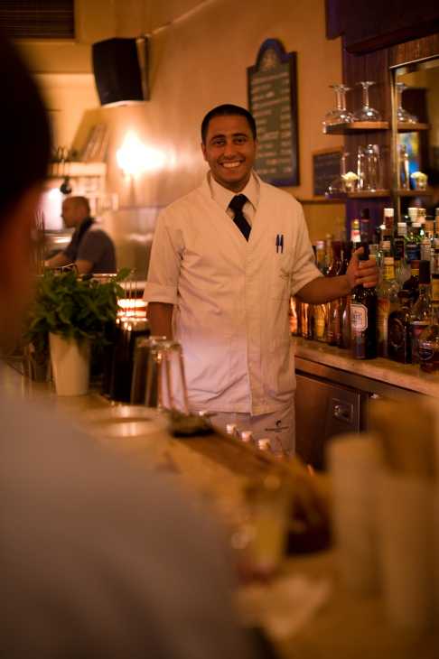 Bartender in white overalls standing behind a bar counter at Dragonfly in Beirut.