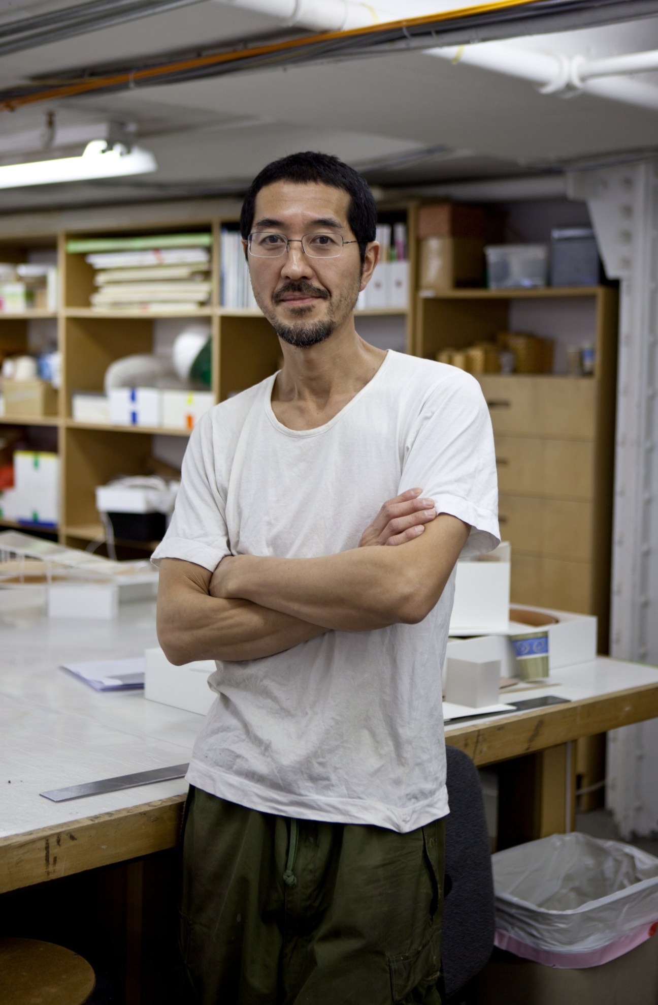 Takeshi Miyakawa stands with arms crossed in Rafael Vinoly architects' model workshop in New York.