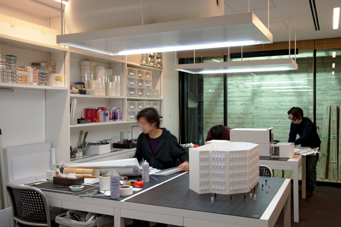Wonderwall studio in Tokyo with model-makers working on architectural models at desks with miniature building structures.