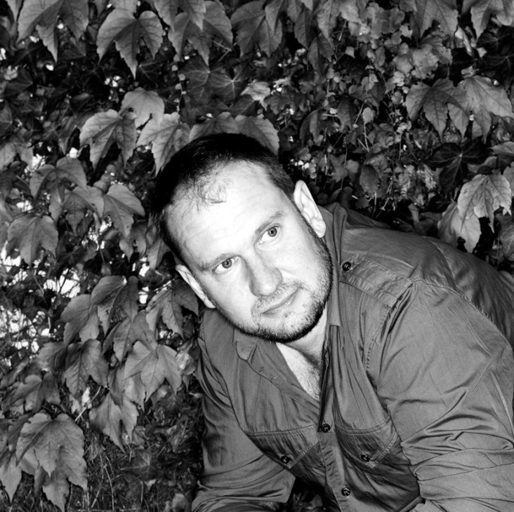 Black and white portrait of Ian Drummond, director of Indoor Garden Design, posed against climbing ivy.