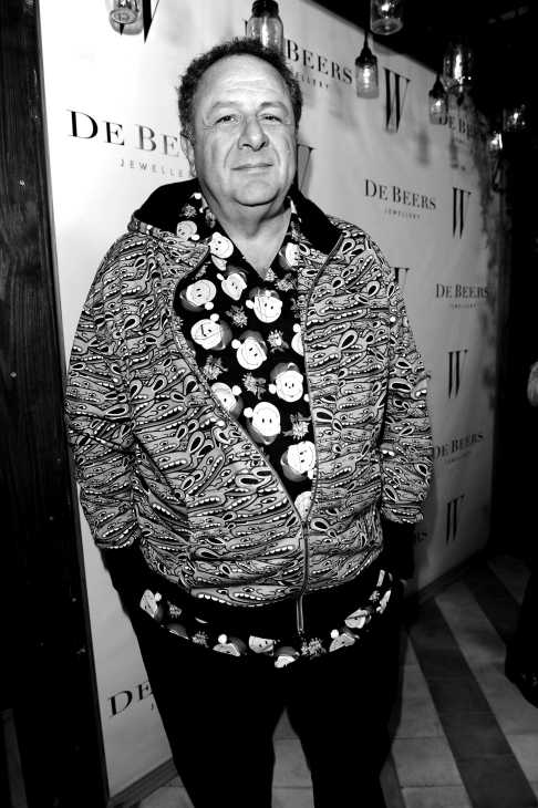 Black and white portrait of a man in patterned jacket and shirt at an event.