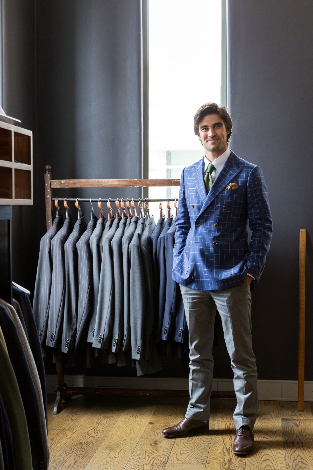 Man in blue blazer standing beside rack of tailored jackets at Oscar Hunt boutique.