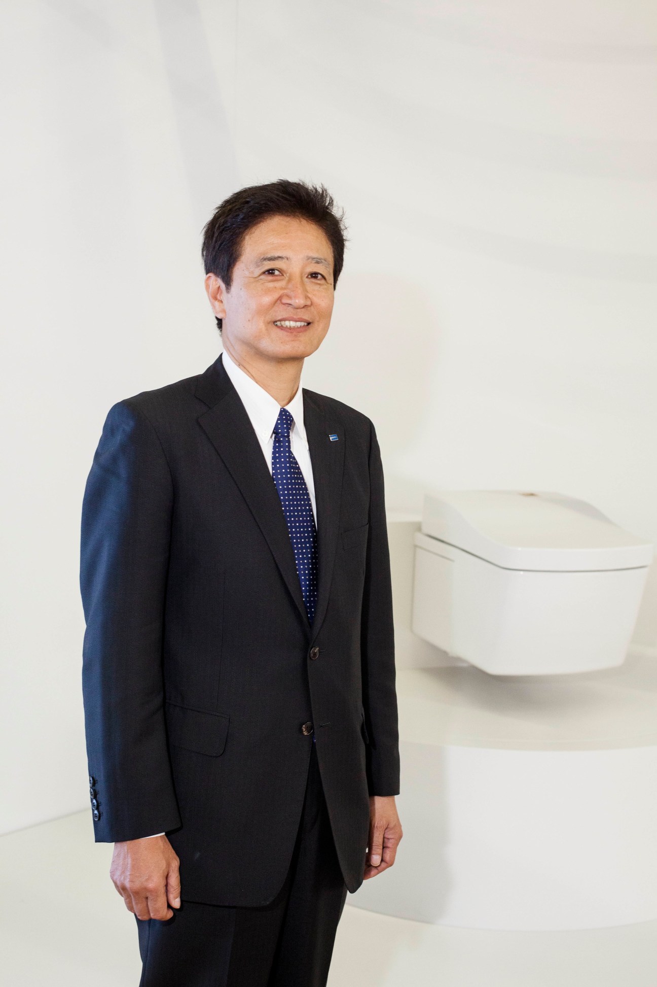 Hiromichi Tabata, director and senior managing executive officer at TOTO, stands in front of a white toilet display.