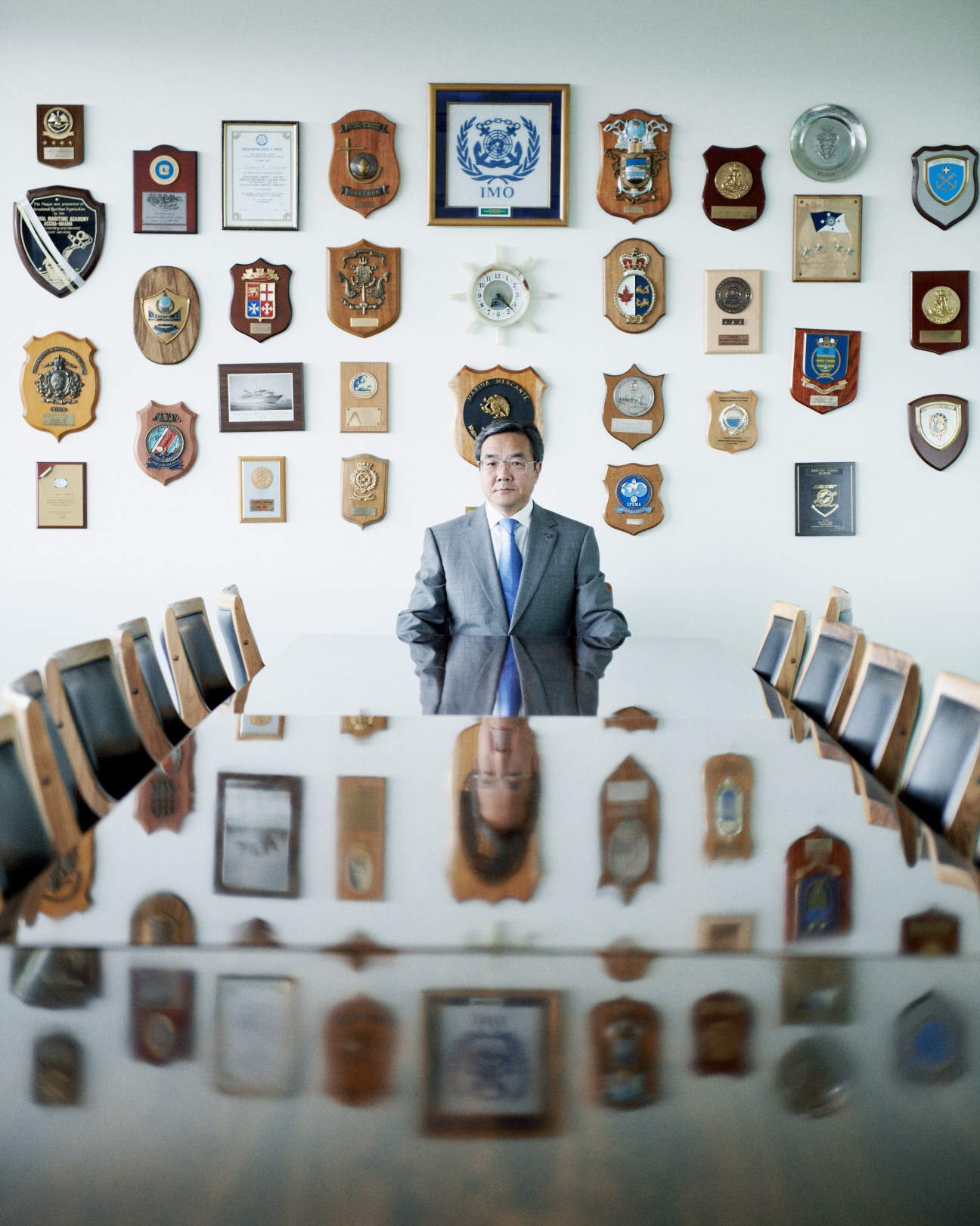 Koji Sekimizu, secretary-general of the International Maritime Organisation, poses in his London office surrounded by maritime awards and plaques.