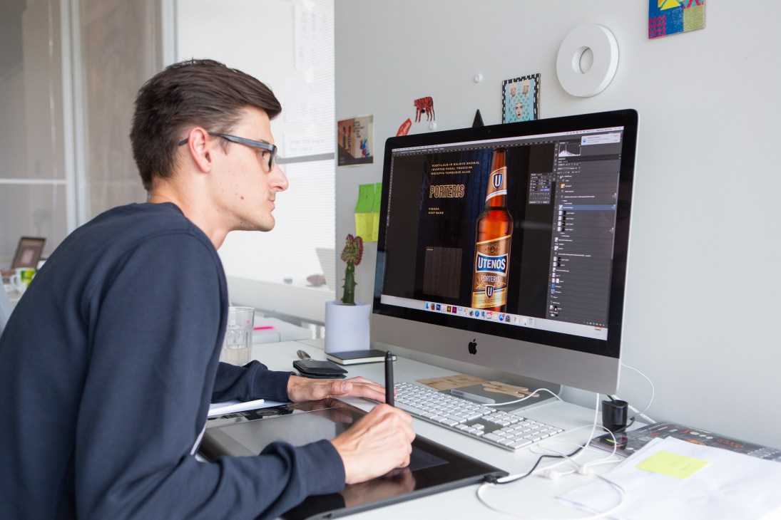 Designer working at computer displaying product packaging design in creative office studio.