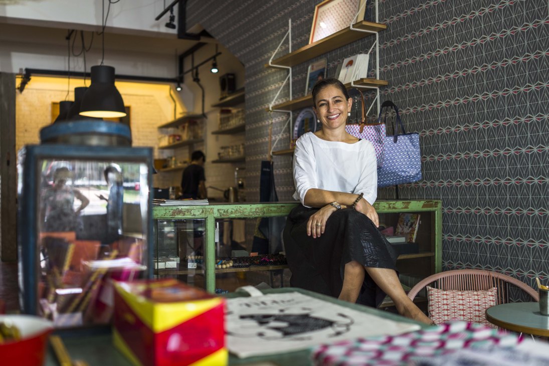 Lisette Scheers poses in her Nala design shop in Kuala Lumpur, surrounded by colorful products and patterned shelving.