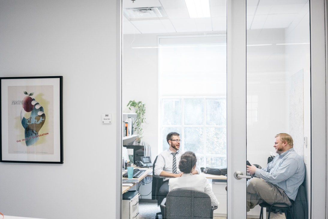 Two people in an office at the German Marshall Fund of the United States in Washington, discussing through a glass partition.