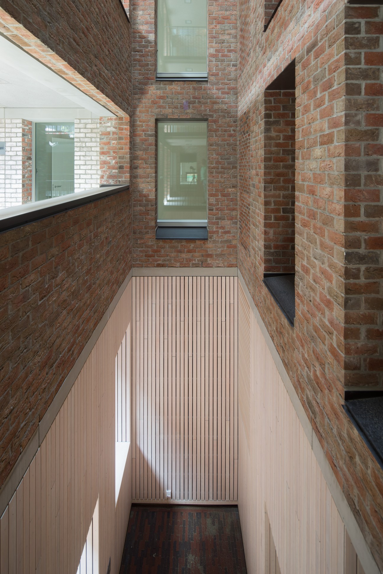 Modern brick station corridor with wooden decking and green-framed windows in minimalist design