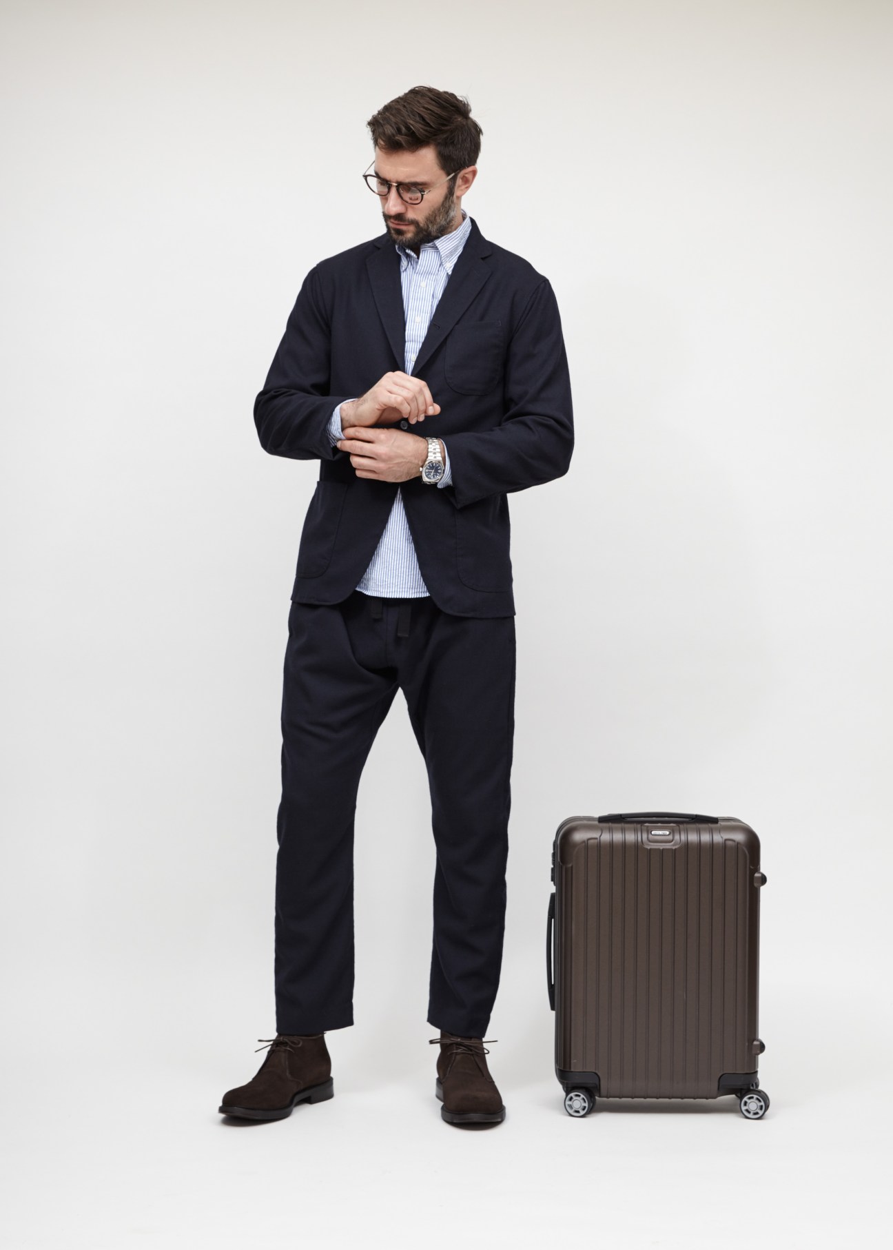 Man in smart business attire with suitcase demonstrating travel outfit styling.