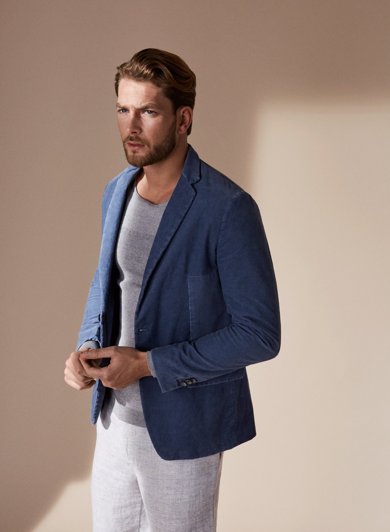 Menswear designer Paul Helbers wearing a navy blazer and grey shirt against a neutral background