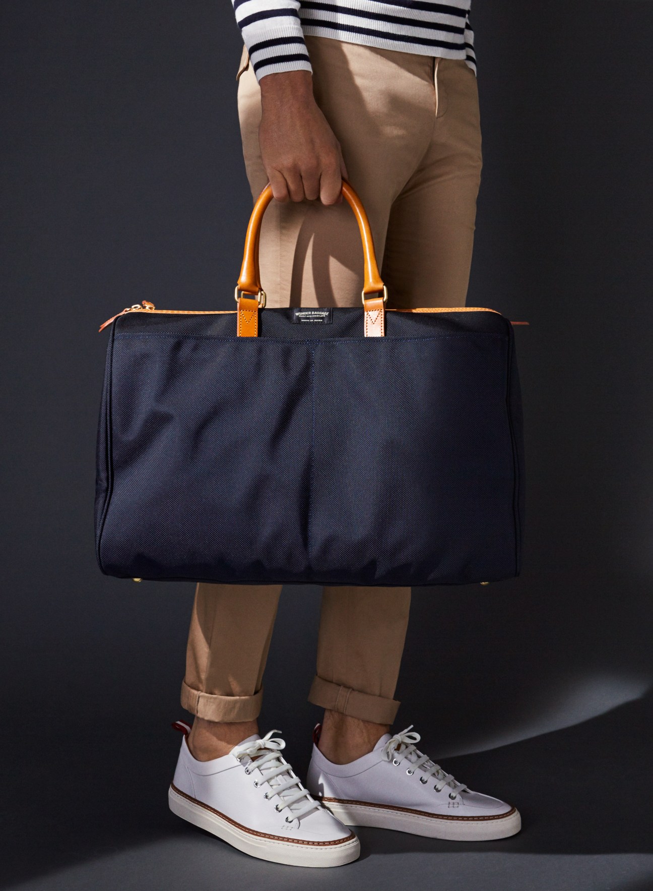 Person holding a Japanese-made ballistic nylon Boston bag with orange leather handles.