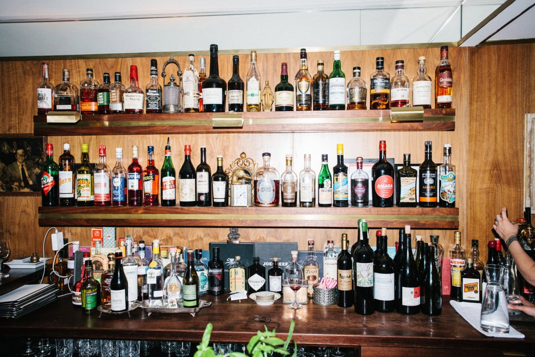 Bar shelves lined with wine bottles and spirits at Nora Gray restaurant in Montréal.