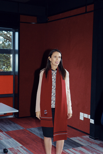 Woman in red coat standing against red wall in modern interior space