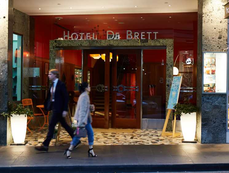 Hotel DeBrett storefront with red facade and mid-century modern signage on Auckland street.