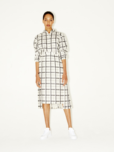 Woman wearing a white grid-pattern button-down shirt dress with white sneakers.