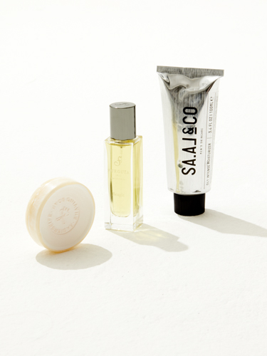 Three sustainable grooming products: a white soap bar, yellow cologne bottle, and white skincare tube labeled Saal & Co.