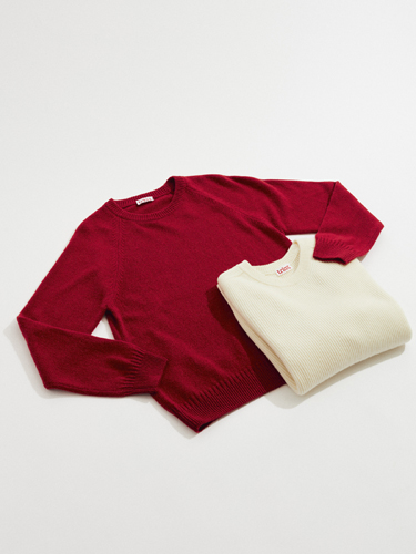 Two knit sweaters displayed on a light background: a burgundy long-sleeved crew neck and a cream-colored sleeveless vest by Tricot.
