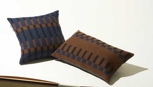 Two patterned wool cushions with geometric dovetail designs in blue and brown tones.