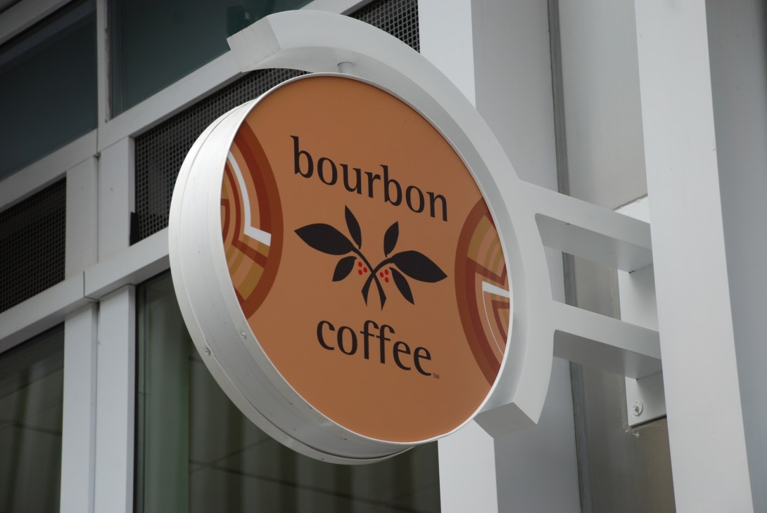 Bourbon Coffee storefront sign with circular brown logo featuring leaf design on white building