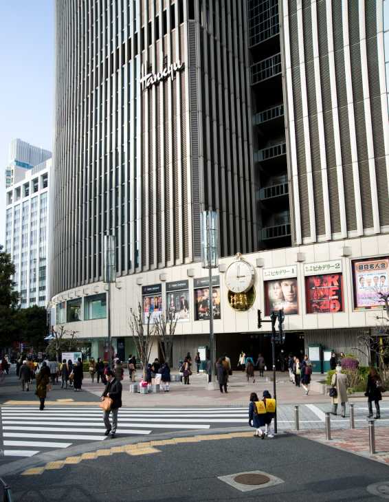 Hankyu department store building in Tokyo's Yurakucho district with vertical ribbed facade and street-level signage.
